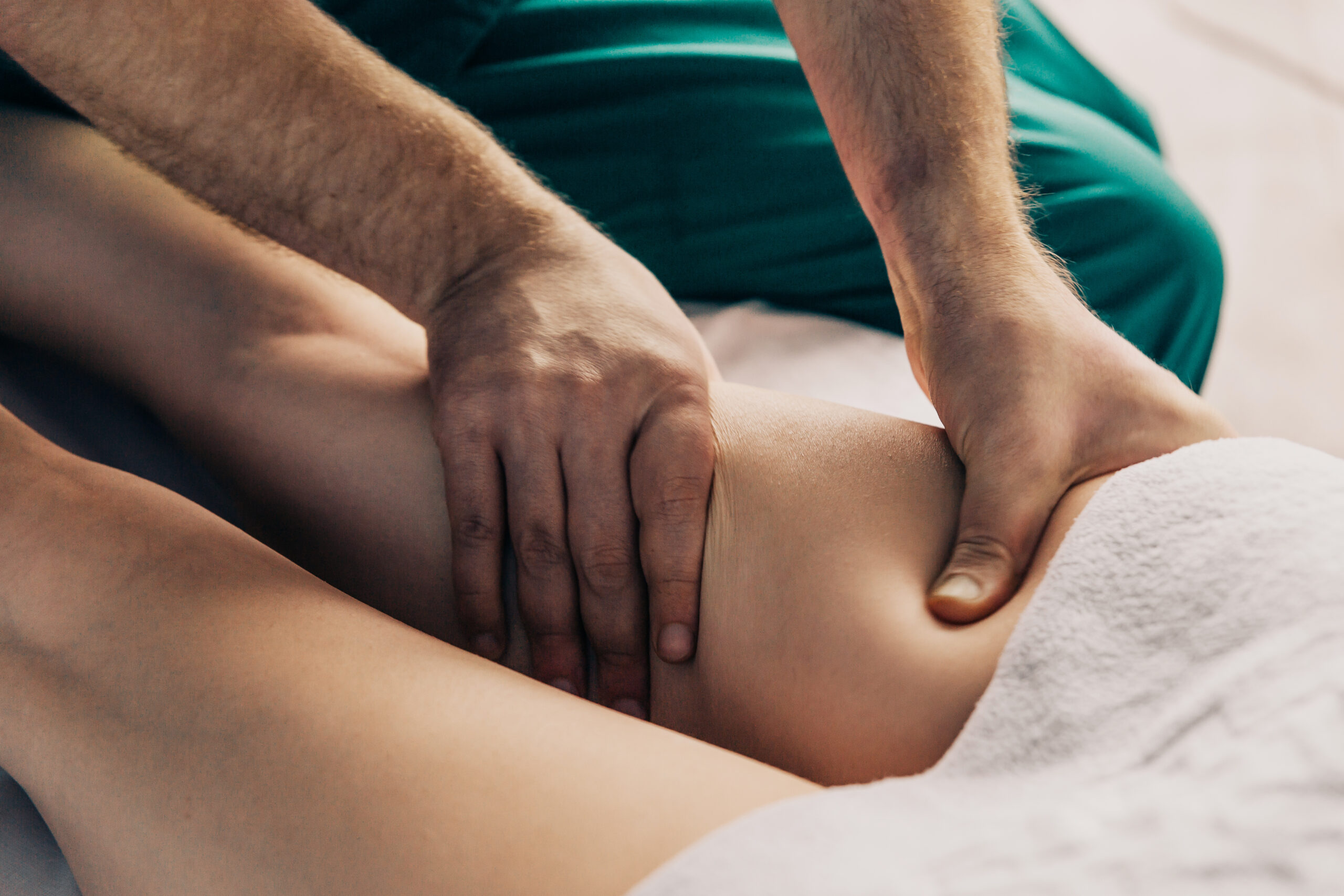 Therapeut führt manuelle Lymphdrainage am Oberschenkel des Patienten durch