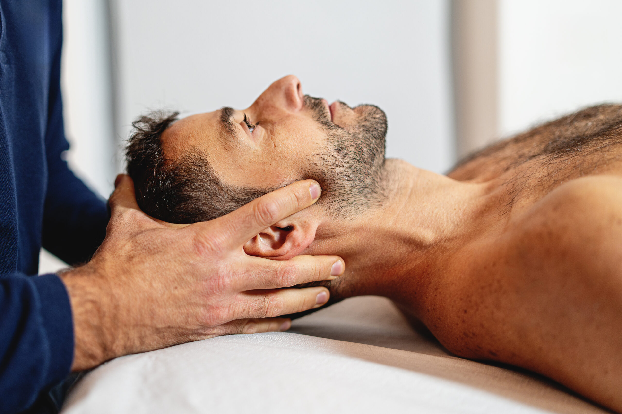 Therapeut führt manuelle Therapie am Kopf des Patienten durch